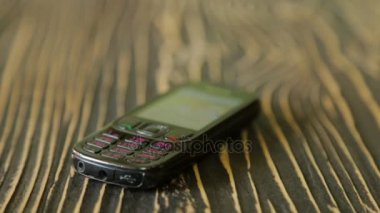 Döşeme masasında eski püskü bir cep telefonu var.