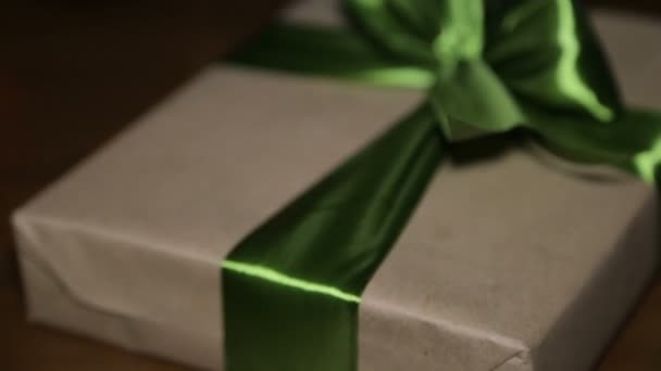 Regalo de Navidad en una caja atada con una cinta verde con un lazo — Vídeo de stock