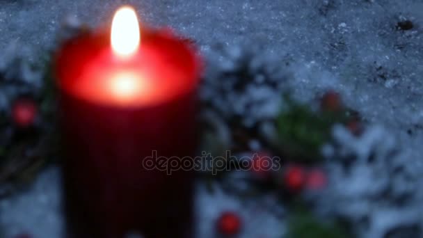 Ett tänt ljus på julafton mot bakgrund av konstgjord snö — Stockvideo