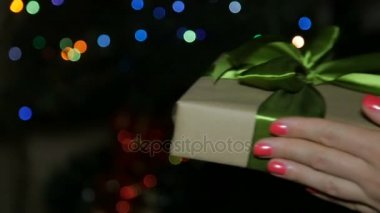 Bir kadın bir çocuk için bir yeni yıl hediye verir. Onu bir kutuya bir bokeh arka plan üzerinde eller