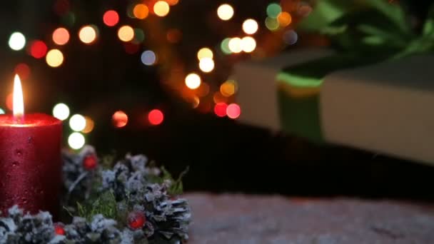 Eine brennende Kerze und eine Geschenkschachtel auf dem Hintergrund eines Bokeh — Stockvideo