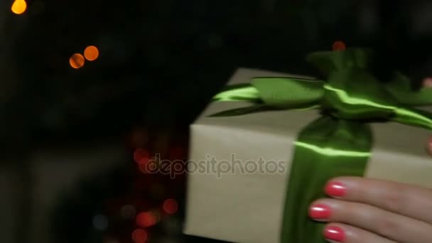 Una mujer le da un regalo de Año Nuevo a un niño. Una caja en sus manos en el fondo de un bokeh — Vídeo de stock