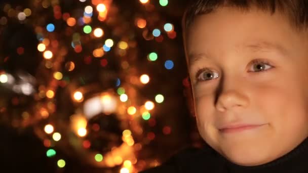 Gezicht Van Een Jongen Tegen Achtergrond Van Kerstverlichting Vervagen — Stockvideo