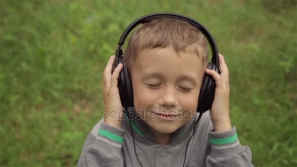 El niño escucha música a través de auriculares — Vídeo de stock