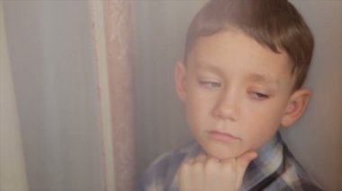 Üzgün bir çocuk pencereden görünüyor