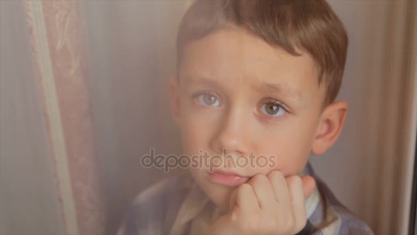 Ein Trauriges Kind Schaut Aus Dem Fenster — Stockvideo