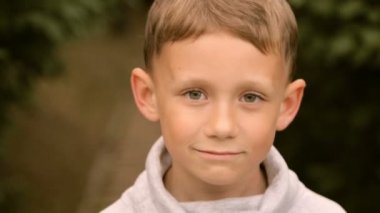 Genç çocuk gülümsüyor ve kameraya poz veriyor.