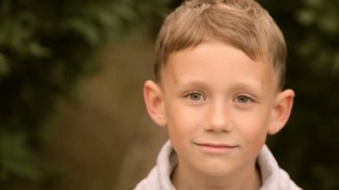 Genç çocuk gülümsüyor ve kameraya poz veriyor.