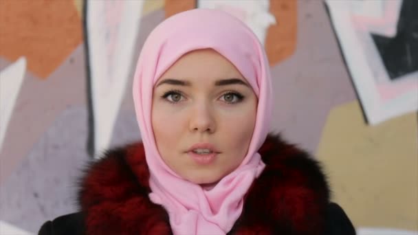 スカーフでイスラム教徒の女性の肖像画に壁の背景に頭が覆われています — ストック動画