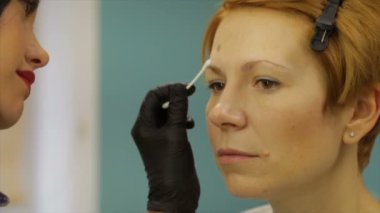 Makyöz kaş dövme bir kadın için yapar.