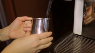 Süt bir profesyonel kahve makinesinde bir kavanoza kırbaçlanan Barista