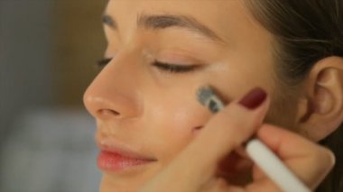 Makyaj sanatçısı kız yüzünde bir ses frekanslı krem koyar.