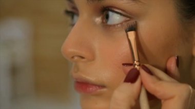 Makyaj sanatçısı kız yüzünde bir ses frekanslı krem koyar.