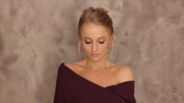 Retrato de una modelo con una bufanda borgoña sobre un fondo gris — Vídeos de Stock