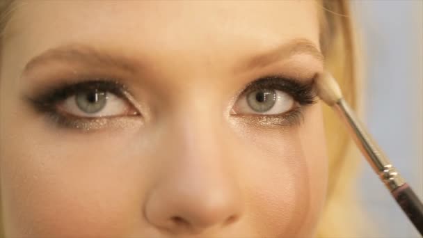 Artist-Make-up, das das Auge eines Mädchens mit hellem Lidschatten in Grundfarbe schminkt