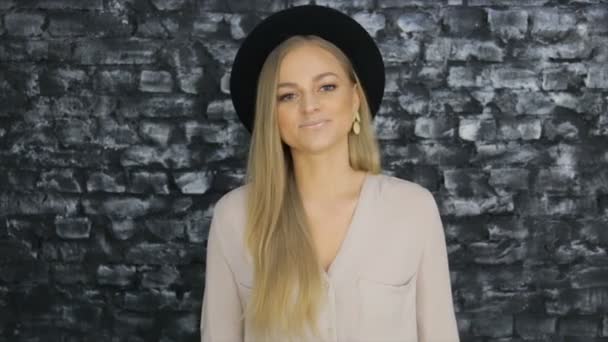 Dziewczyna w czarny kapelusz i szara koszula pozowanie pozytywny ścianę tekstury — Wideo stockowe