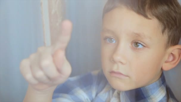 Ten chlapec nakreslí prstem na okno — Stock video