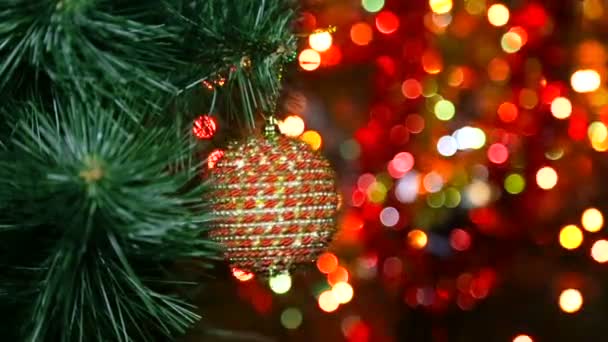 Χριστουγεννιάτικο παιχνίδι σε ένα χριστουγεννιάτικο δέντρο ενάντια σε μια γιρλάντα στη θολούρα — Αρχείο Βίντεο