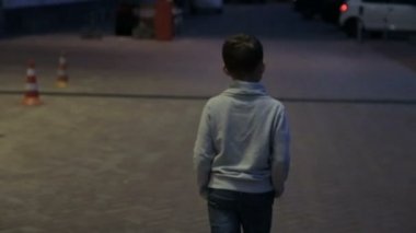 Çocuk gece şehrinde yürüyor.