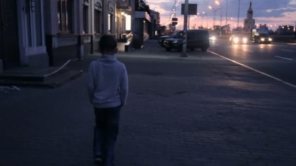 El niño camina por la ciudad nocturna — Vídeo de stock