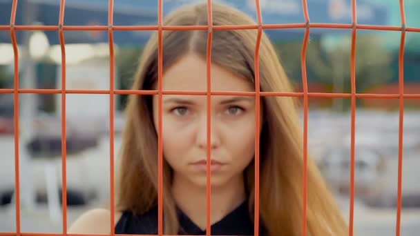 Porträt eines Mädchens auf dem Hintergrund des Gitters — Stockvideo