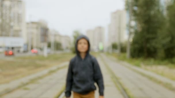 Мальчик в черном капюшоне на улице — стоковое видео