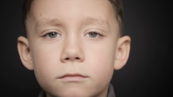 Um menino frio close-up em um fundo preto — Vídeo de Stock