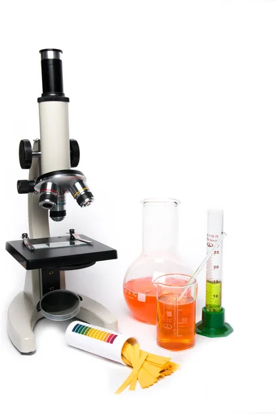 Microscope and laboratory glassware on a white background — Stock Photo, Image