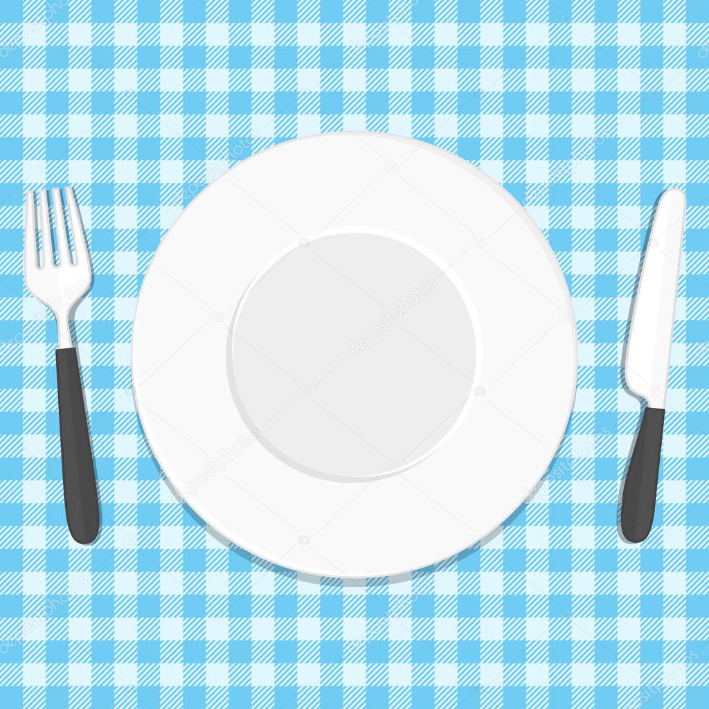 Plate knife and fork on tablecloth.