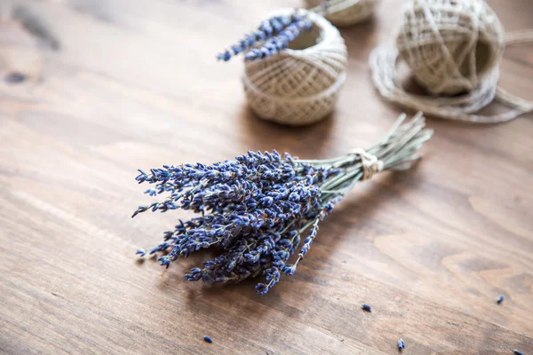 Bos van lavendel en spoelen van wol op houten achtergrond — Stockfoto