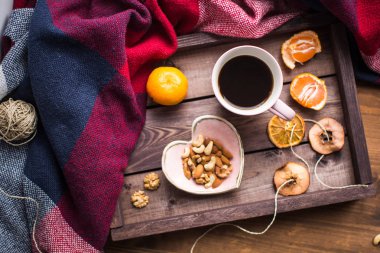 bir fincan kahve, fındık ve penceresindeki turuncu ile ahşap tepsi