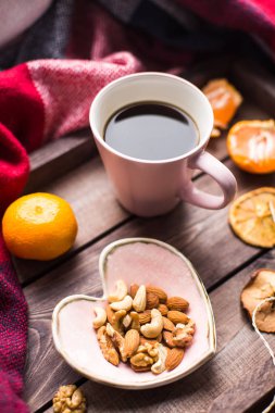 bir fincan kahve, fındık ve penceresindeki turuncu ile ahşap tepsi