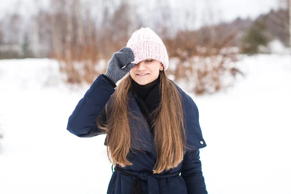 Привлекательная улыбающаяся молодая женщина, гуляющая в зимнем лесу в вязании — стоковое фото