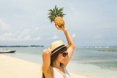 ananas sahilde tutan şapkalı kız