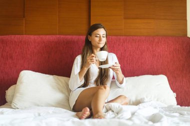 genç kız yatakta çay içme beyaz elbise içinde