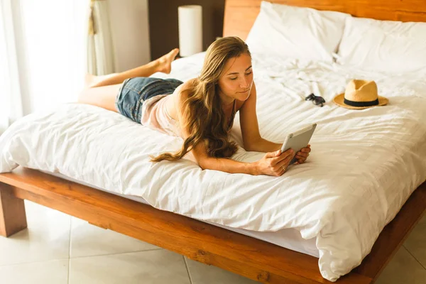 Young woman with tablet lying on the bed