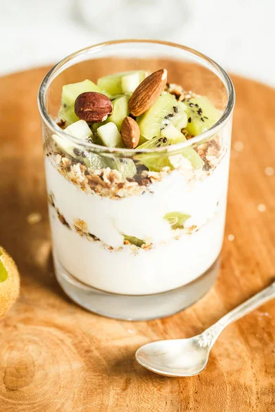 Glas Joghurt mit Müsli und Kiwi-Scheiben. Frühstückskonzept Stockbild