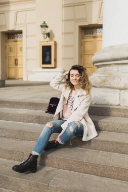 Genç güzel kız tiyatronun basamaklarında oturur