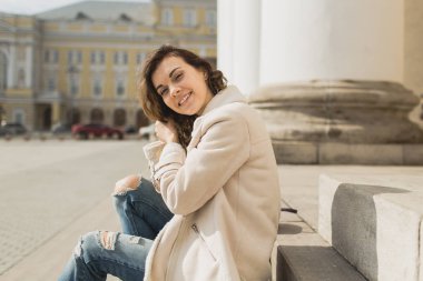 Genç güzel kız tiyatronun basamaklarında oturur