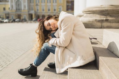 Genç güzel kız tiyatronun basamaklarında oturur