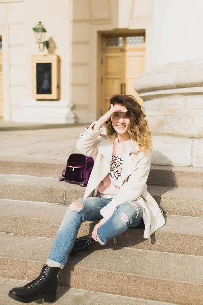 Genç güzel kız tiyatronun basamaklarında oturur