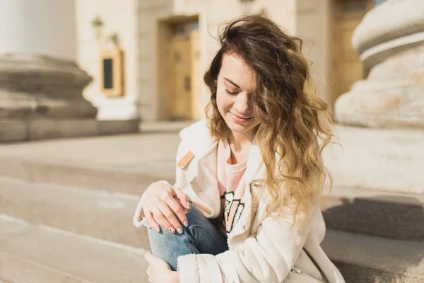 Young beautiful girl sits on the steps of the theater — Stock Photo, Image