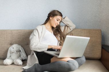 Kız evde kanepede otururken dizüstü bilgisayar ile