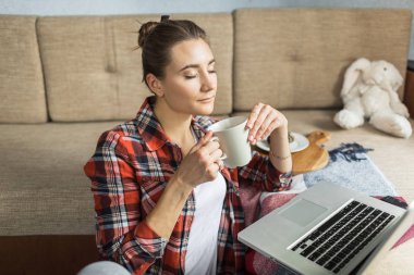 kadın kanepede evde çay içiyor