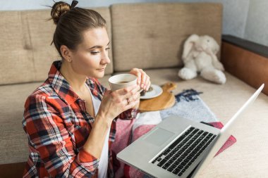 kadın kanepede evde çay içiyor