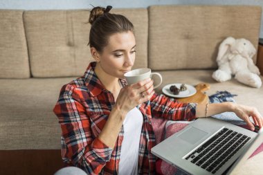kadın kanepede evde çay içiyor