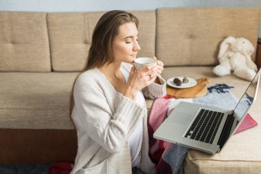 kadın kanepede evde çay içiyor
