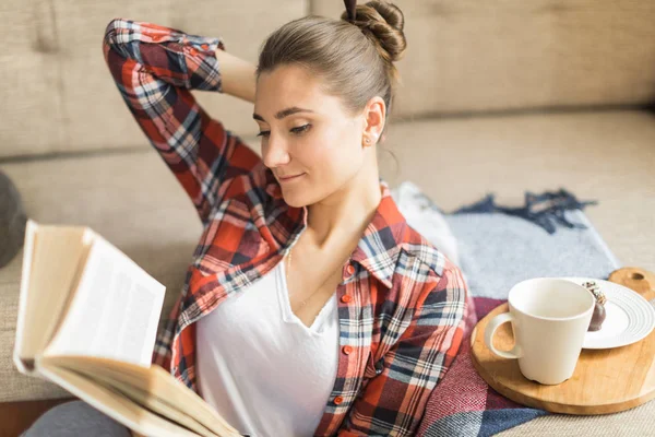 woman reads book at home on the couch