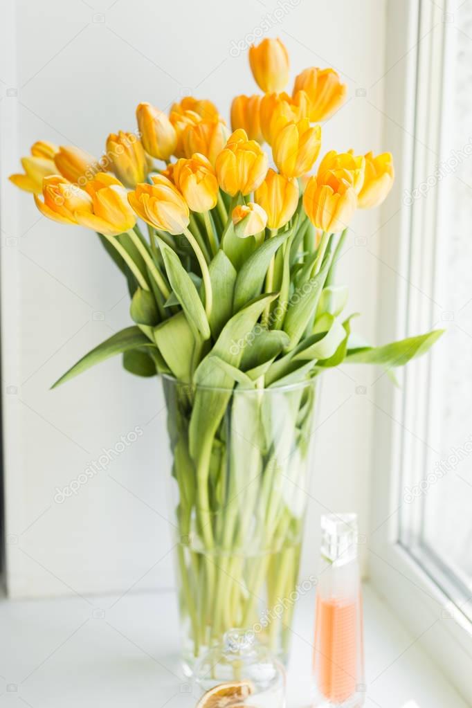 Vase with yellow tulips on the window