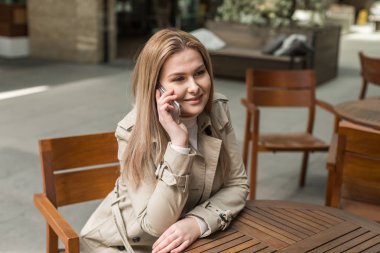  elinde bir telefon ile bir masada oturan kız